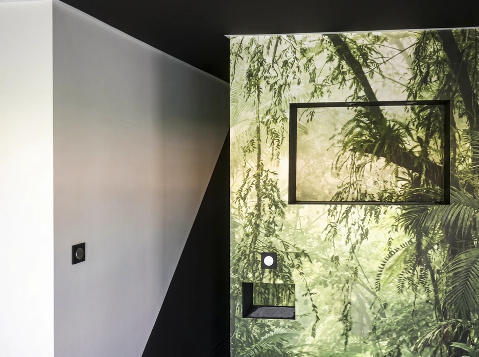 Couloir moderne avec cloison angulaire noire contrastant avec un mur blanc