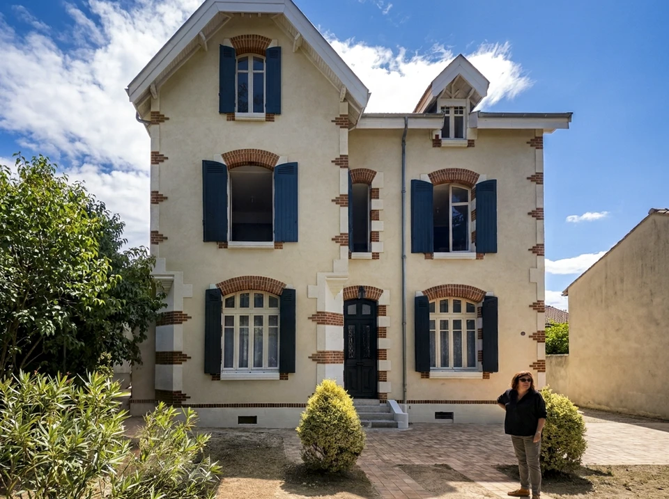 Extérieur, personne appliquant une lasure ou teinture sur des volets en bois avec un pinceau plat